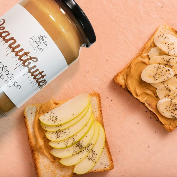 Φιστικοβούτυρο σε βάζο της Pimpiri flavours και φέτες ψωμιού με φυστικοβούτυρο και φρούτα